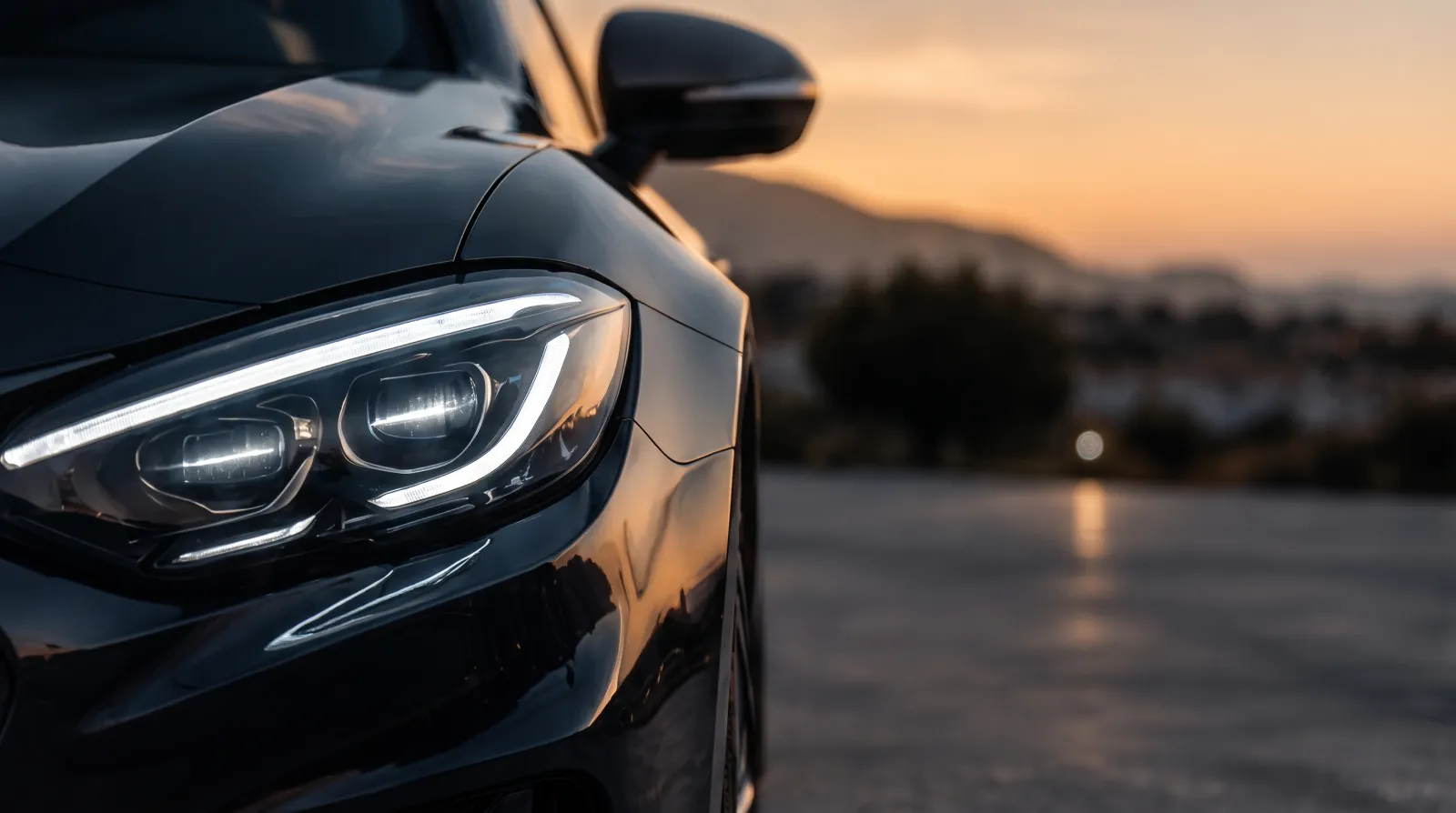 Faro LED de un coche negro de gama alta al atardecer